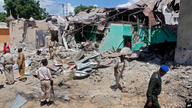 Somali soldiers look at the destroyed houses amidst the wreckage of a car bomb blast in Mogadishu, Somalia, May 17, 2017. Three bomb disposal experts were killed as they were trying to dismantle the car laden with explosives, according to police.