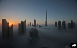 The sun rises over the city skyline with the Burj Khalifa, world's tallest building in 2016