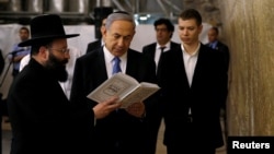 FILE PHOTO: Israel's Prime Minister Benjamin Netanyahu (C) reads a prayer with Western Wall Rabbi Shmuel Rabinowitz (L) as his son Yair (R) stands next to him, at the Western Wall, Judaism's holiest prayer site, in Jerusalem's Old City March 18, 2015.