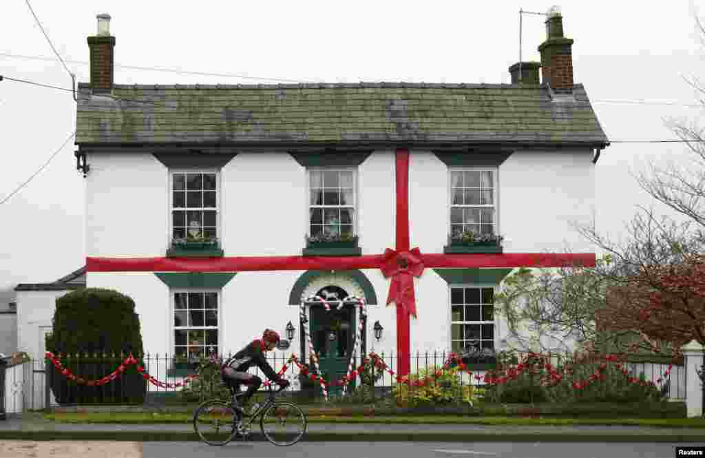 A man cycles past a house decorated as a Christmas present in Scholar Green, northern Britain.