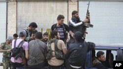This citizen journalism image provided by Edlib News Network (ENN), purports to show Syrian rebels gathered on their vehicle in the northern town of Kfar Nebel, in Idlib province, Syria, June 5, 2012.