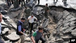 Enspektè siryen sou plas apre yon eskplozyon kraze biwo sèvis sekrè a nan Damas -- 10 me 2012 (Foto VOA).