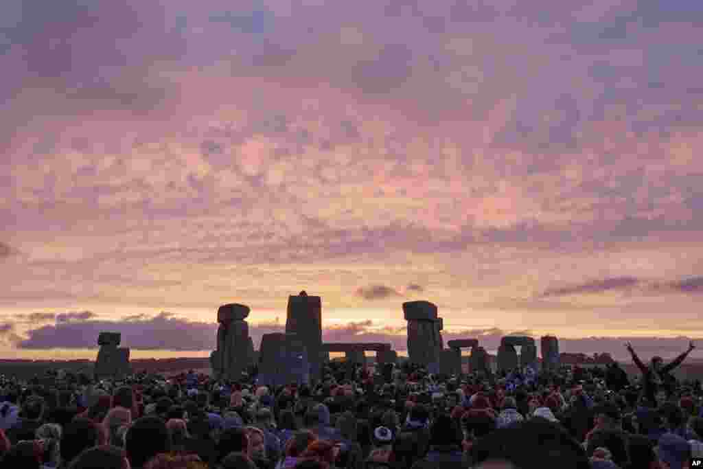The sun rises as thousands of revelers gather at the ancient stone circle Stonehenge to celebrate the Summer Solstice, the longest day of the year, near Salisbury, England.