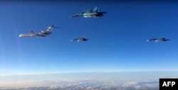 A video grab made on March 15, 2016, shows an image taken from a footage made available on the Russian Defence Ministry's official website on March 15, 2016, reportedly showing Russian Su-34 bombers and a Tupolev Tu-154 transport plane (L) flying above an unknown location on their way from the Hmeimim airbase in Syria to their permanent bases in the Russian Federation.