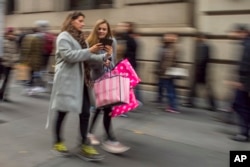 Shoppers carry their purchases as they walk along Fifth Avenue on Black Friday in New York, Friday, Nov. 25, 2016. Stores opened their doors Friday for what is still one of the busiest days of the year, even as the start of the holiday season edges ever earlier and online sales increase.