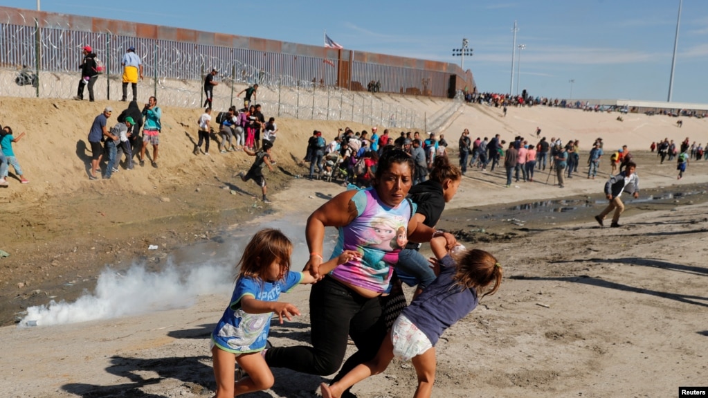 Una familia de migrantes, parte de la caravana de miles que viaja desde Centroamérica hacia Estados Unidos, corre para escapar del gas lacrimógeno en la frontera entre Estados Unidos y México en Tijuana, el 25 de noviembre del 2018
