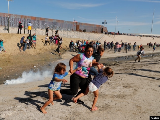 Una familia de migrantes, parte de la caravana de miles que viaja desde Centroamérica hacia Estados Unidos, corre para escapar del gas lacrimógeno en la frontera entre Estados Unidos y México en Tijuana, el 25 de noviembre del 2018.