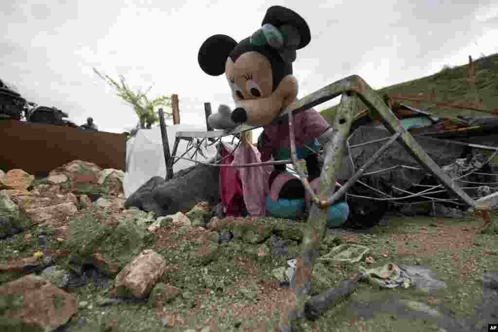 A Minnie Mouse doll lays inside the frame of a warped iron bed among the debris of a home destroyed by Hurricane Matthew, in Port-a-Piment, Haiti, Oct. 19, 2016.