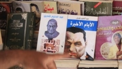 An Egyptian displays books showing cartoons on the covers of former Egyptian President Hosni Mubarak in Cairo, Egypt, May 23, 2011