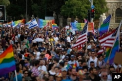 Participants wave flags and hold signs during the annual Gay Pride parade in Jerusalem, June 6, 2019.