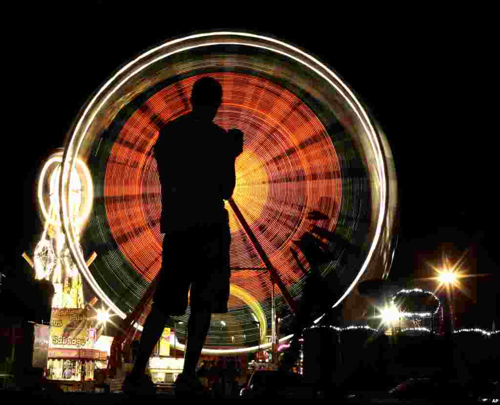 A person is silhouetted while watching the Ferris wheel at the Iowa State Fair in Des Moines, USA, Aug. 16, 2015.