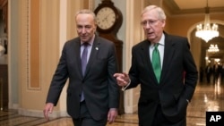 Pemimpin Senat Mayoritas Mitch McConnell (Republik) dan Pemimpin Senat Minoritas Chuck Schumer (Demokrat, kanan), berjalan menuju ruang sidang setelah berkolaborasi untuk kesepakatan pendanaan dua tahun, yang mencapai sekitar $400 milyar untuk Pentagon dan program domestik.