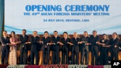 FILE- In this June 24, 2016, file photo, Laotian Prime Minister Thongloun Sisoulith, sixth from left, and Laotian Foreign Minister Saleumxay Kommasith, sixth from right, join their hands with Southeast Asian foreign ministers, from left, an unidentified d