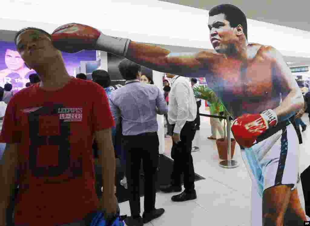 A Filipino fan poses before a standee of Muhammad Ali at an exhibit of photos and memorabilia launched last week to pay tribute to Muhammad Ali, in Quezon city, Philippines, June 10, 2016. 