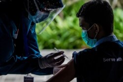Seorang petugas kesehatan memvaksinasi rekannya saat vaksinasi massal untuk tenaga medis dan lansia di Bogor, Jawa Barat, 11 Februari 2021. (Foto: ADITYA AJI / AFP)