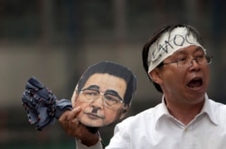 FILE - Ning Ye holds up a mask of former Chinese Premier Li Peng as part of a demonstration in New York on June 3, 2012 to honor of the 23rd anniversary of the The Tiananmen Square Protests which occurred in China on June 4, 1989.