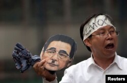 FILE - Ning Ye holds up a mask of former Chinese Premier Li Peng as part of a demonstration in New York on June 3, 2012 to honor of the 23rd anniversary of the The Tiananmen Square Protests which occurred in China on June 4, 1989.
