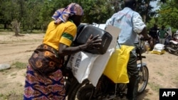 FILE - A Cameroonian displaced woman is seen loading her donated food onto a motorcycle outside a distribution center in Koza, in the extreme northern province, west of the Nigerian border, Sept. 14, 2016