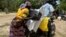 FILE - A Cameroonian displaced woman is seen loading her donated food onto a motorcycle outside a distribution center in Koza, in the extreme northern province, west of the Nigerian border, Sept. 14, 2016
