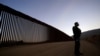 FILE - Border Patrol agent Justin Castrejon stands in front of newly replaced border wall sections, near Tecate, California, Sept. 24, 2020.