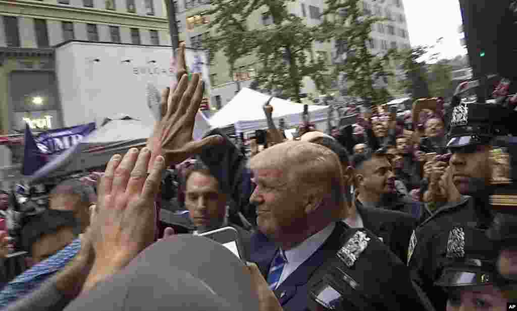 In this image made from video, Republican presidential candidate Donald Trump greets supporters outside his Trump Tower building in New York on Saturday.