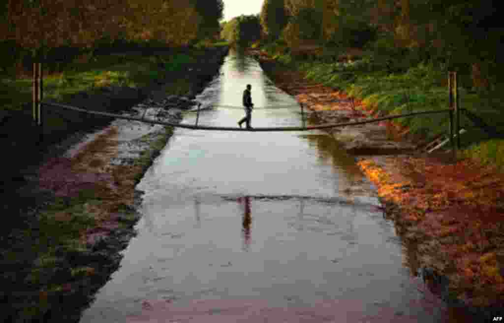 A man walks across a foot-bridge over the River Marcal containing the toxic red sludge that spilled Monday from a giant industrial container near Mersevat, Hungary, Thursday, Oct. 7, 2010. "Life in the River Marcal has been extinguished," Rescue official 