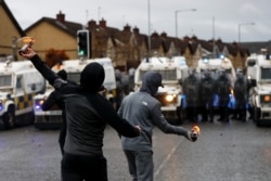 FILE - Rioters throw burning bottles at the police on the Springfield Road as protests continue in Belfast, Northern Ireland, April 8, 2021.