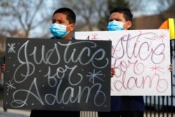 FILE - Jacob Perea, 7, left, and Juan Perea, 9, hold signs as they attend a news conference April 6, 2021, following the death of 13-year-old Adam Toledo, who was shot by a Chicago Police officer .