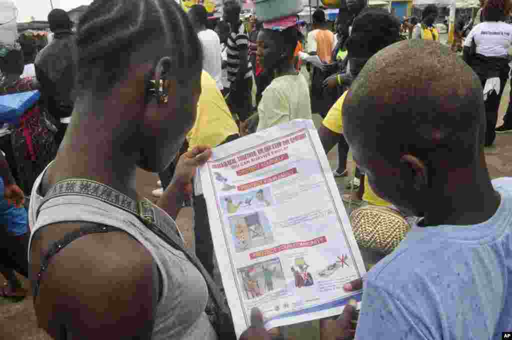 Liberian children read a leaflet with guidelines to protect the community from the Ebola virus, in Monrovia, Liberia, Oct. 13, 2014.