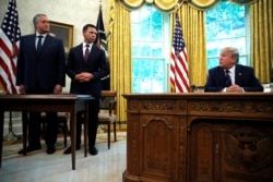 President Donald Trump looks to Acting Secretary of Homeland Security Kevin McAleenan, second from left, and Guatemalan Interior Minister Enrique Degenhart as he speaks to the media in the Oval Office of the White House in Washington, July 26, 2019.