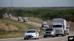 Konvoi truk bantuan Rusia membawa bantuan kemanusiaan untuk Ukraina dikawal mobil polisi memasuki perbatasan di kota Rusia, Donetsk, Rostov-on-Don, Rusia, 17 Agustus 2014.