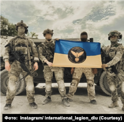 Бійці Міжнародного легіону при ГУР із прапором та символікою. Instagram/ international_legion_diu