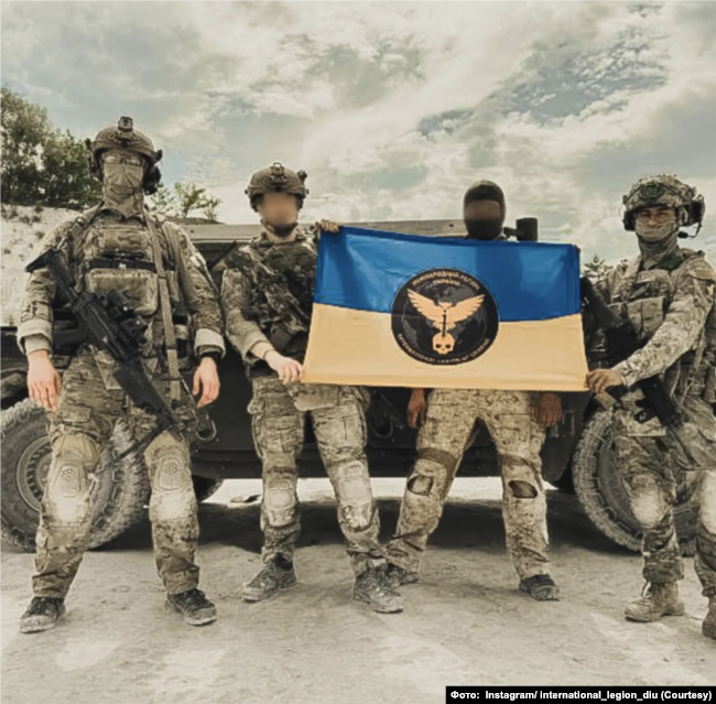 Бійці Міжнародного легіону при ГУР із прапором та символікою. Instagram/ international_legion_diu