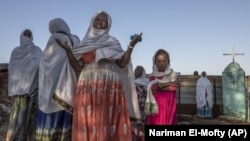 A Tigrayan woman who fled the conflict in Ethiopia's Tigray region prays after Sunday Mass ends at a nearby church, in Umm Rakouba refugee camp in Qadarif, eastern Sudan, Nov. 29, 2020. (AP Photo/Nariman El-Mofty)