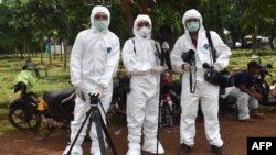 FILE - This picture taken with a self-timer shows AFP journalists in protective gear while reporting on a COVID-19 story at Pondok Ranggon cemetery in Jakarta, May 6, 2020.
