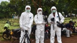 FILE - This picture taken with a self-timer shows AFP journalists in protective gear while reporting on a COVID-19 story at Pondok Ranggon cemetery in Jakarta, May 6, 2020.