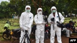 FILE - This picture taken with a self-timer shows AFP journalists in protective gear while reporting on a COVID-19 story at Pondok Ranggon cemetery in Jakarta, May 6, 2020.