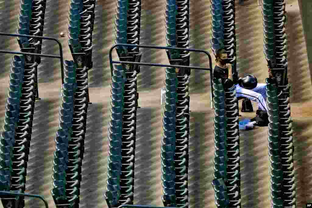 A lone foul ball sits in an aisle as an Arizona Diamondbacks ballboy watches from the stands during the sixth inning of a baseball game against the San Diego Padres, Aug. 15, 2020, in Phoenix, Arizona.