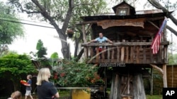Dr. Jason Barnes, top right, sits in his kids' treehouse while his family plays in their backyard, April 18, 2020, in Corpus Christi, Texas. 