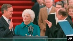 En esta foto del 20 de enero de 1989, George H.W. Bush jura al cargo como presidente número 41 de Estados Unidos ante el presidente de la Corte Suprema, William Rehnquist, mientras la primera dama Barbara Bush sostiene la Biblia.