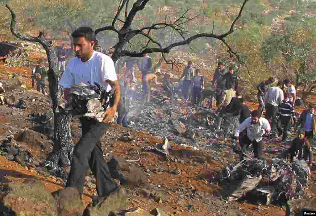 一个人2012年11月28日在达雷特艾扎提着一架被击落的效忠叙利亚总统阿萨得的战机的部分残骸。