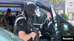 German special police leave their cars in this still image taken from video after a masked man with a gun and ammunition belt opened fire in a cinema complex and took hostages before police killed him, in Viernheim, near Frankfurt, Germany, June 23, 2016.