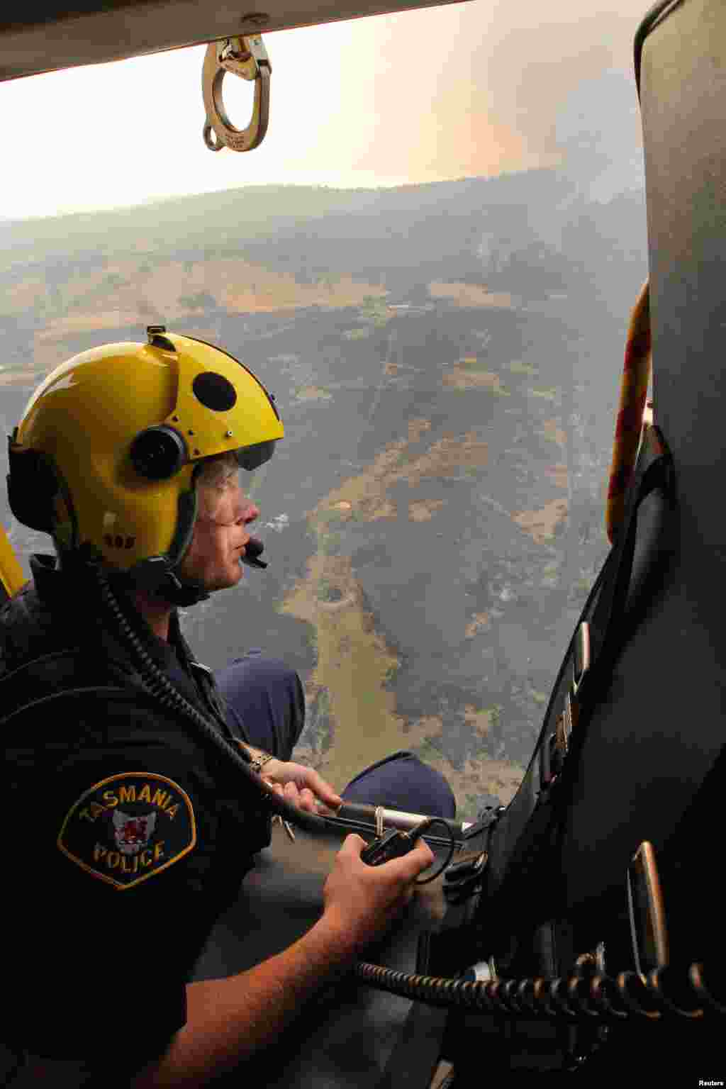 Anggota awak helikopter penyelamatan polisi Matthew Drumm mengamati kebakaran di Dunnalley, sebelah timur Hobart, negara bagian Tasmania (5/1).