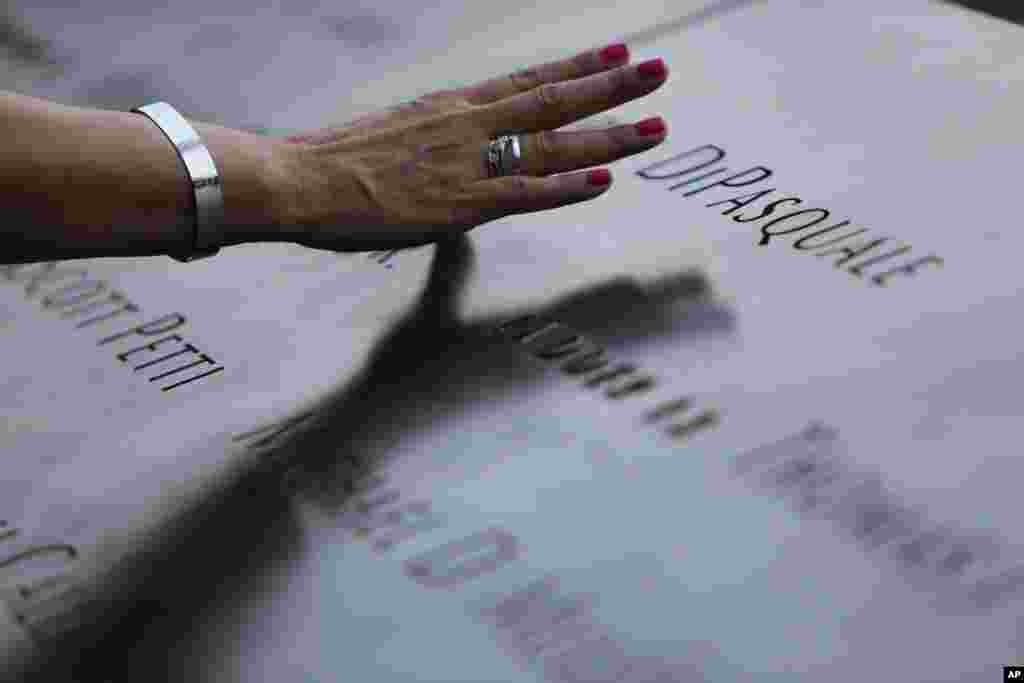 A woman touches the stone with names of the 9/11 victims at the 9/11 Memorial during ceremonies marking the 12th anniversary of the attacks on the World Trade Center in New York, Sept. 11, 2013.