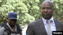 Zimbabwe's Prosecutor General Johannes Tomana (R) arrives escorted by policemen at the Harare Magistrates court, Feb. 2, 2016. 