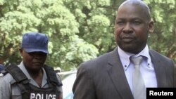 FILE: Zimbabwe's Prosecutor General Johannes Tomana (R) arrives escorted by policemen at the Harare Magistrates court, Feb. 2, 2016. 