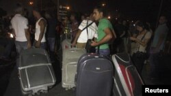 Passengers carrying baggage try to pass, after main road leading to Beirut airport was blocked by relatives of the 11 Lebanese Shi'ite pilgrims who were abducted in Syria, August 15, 2012. 