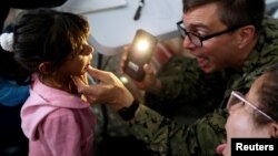 FILE - Kamila, daughter of Yenymar Vilches, a Venezuelan migrant, is attended by personnel of the USNS Comfort at Divina Pastora High School in Riohacha, Colombia, Nov. 26, 2018.