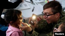 Kamila, daughter of Yenymar Vilches, Venezuelan migrant, is attended by personnel of the ship of the United States Navy Hospital USNS Comfort at Divina Pastora High School in Riohacha, Colombia, Nov. 26, 2018.