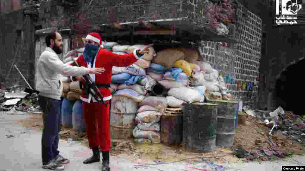 Free Syrian Army fighter in a Santa Claus suit offers Homs resident directions in the Old City, January 1, 2013 (Lens Young Homsi)